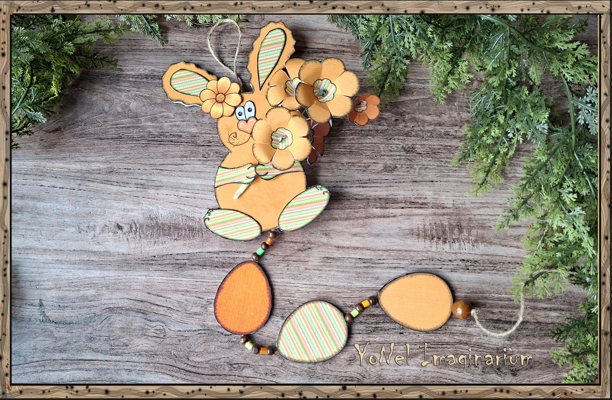 Handmade 3D printable Easter bunny wall hanging with layered paper flowers and decorative Easter eggs on a rustic wooden background.